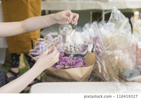 一位年輕女子在工坊裡用乾燥花製作時尚的風鈴。 118419327