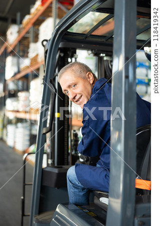 Elderly man worker works on loader in warehouse 118419342