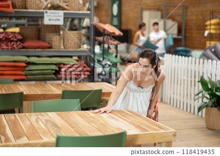 Young woman choosing wooden patio table in garden store 118419435
