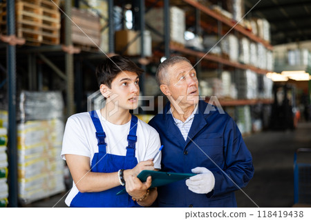Guy check papers invoices together with mature employee and revise availability of goods in stock Guy check papers invoices together with mature employee and revise availability of goods in stock 118419438