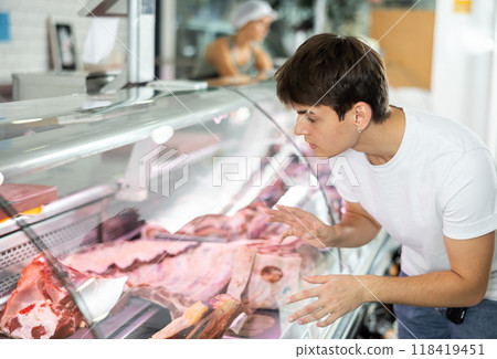 Young man purchaser buying meat in butcher shop Young man purchaser buying meat in butcher shop 118419451