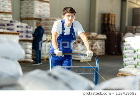 Guy worker carries pushes cart trolley for cargo transportation. 118419582