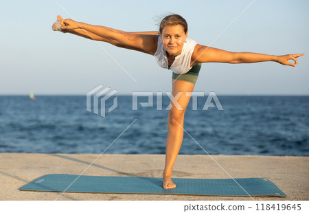 Yoga pose called parivritta performed by a girl on seashore 118419645