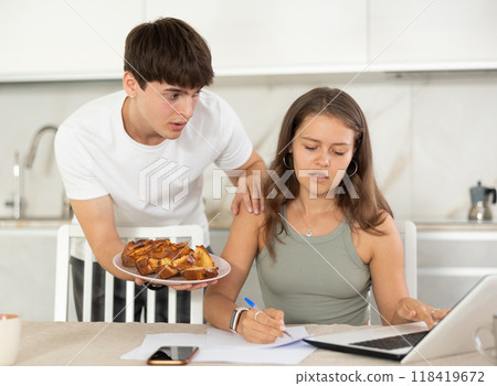 Young guy offering pie to woman working at laptop 118419672