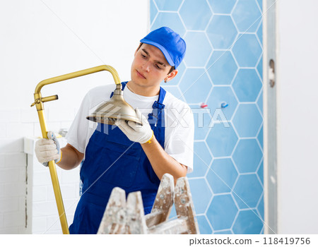 Young builder assembling shower set before fixing to wall Young builder assembling shower set before fixing to wall 118419756