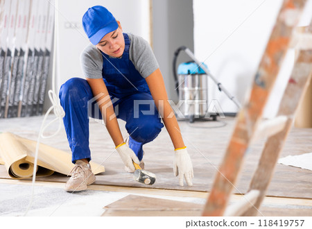 Young female builder puts laminate flooring Young female builder puts laminate flooring 118419757