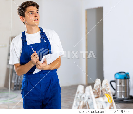 Repairman checking project documentation, planning renovation works in new apartment 118419764