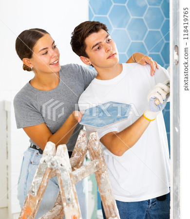 Young couple laying ceramic tiles on walls during home renovation 118419765