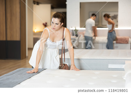 Young woman choosing convenient mattress in furniture shop Young woman choosing convenient mattress in furniture shop 118419801