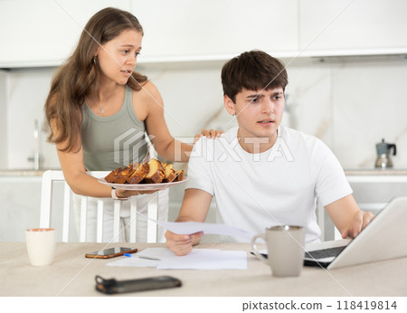 Young woman offering pie to guy working at laptop Young woman offering pie to guy working at laptop 118419814