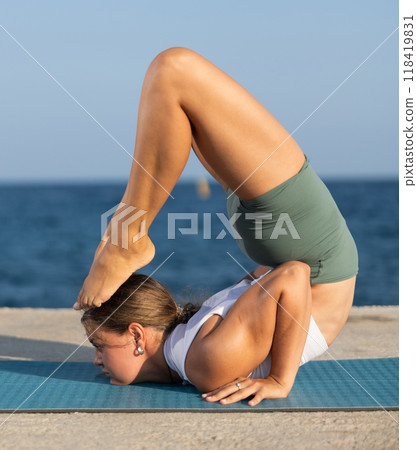 Various yoga poses performed by a sporty girl on sunny seaside 118419831