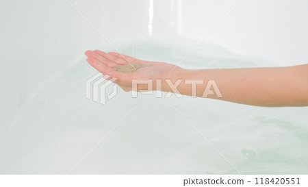 Image for shower gel advertisement with model hand holding shower gel in a bathtub filled with clean water. Minimalist space but clean creates a comfortable feeling 118420551