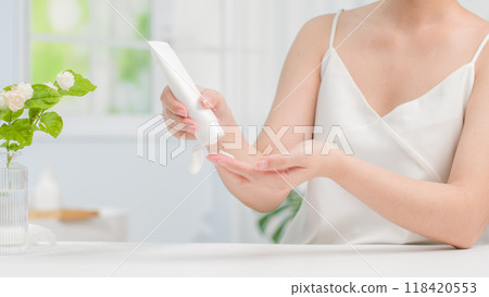 Photo template for skin care product advertisements with the image of a female model squeezing a tube of cream ready to apply to the skin in the setting of a minimalist bathroom with vases of flowers. Photo template for skin care product advertisements with the image of a female model squeezing a tube of cream ready to apply to the skin in the setting of a minimalist bathroom with vases of flowers. 118420553