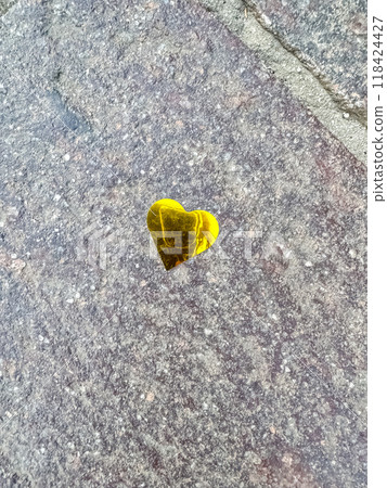 small, golden heart-shaped sticker placed on a textured stone and brick pathway. High quality photo 118424427