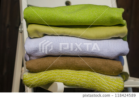 stack of green and beige sweaters on white chair . High quality photo 118424589