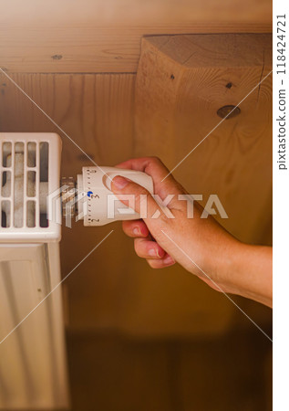 a woman's hand setting the room temperature By Thermostat in wooden house. High quality photo 118424721