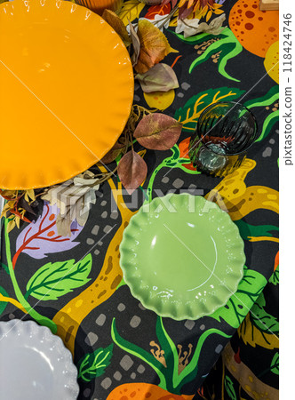 green and orange and white plates on colourful tablecloth and green glass . High quality photo 118424746
