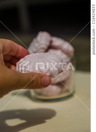women hand holds pink marshmallows and more marshmallows on background in cup . High quality photo women hand holds pink marshmallows and more marshmallows on background in cup . High quality photo 118424833