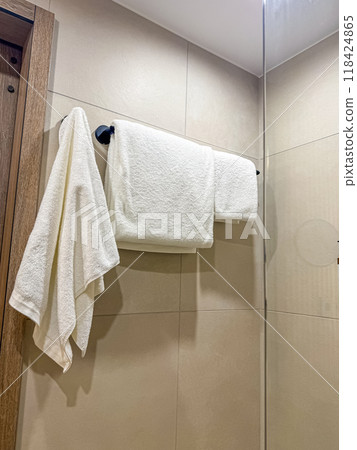 White terry towels hangs in the bathroom on the hanger. High quality photo White terry towels hangs in the bathroom on the hanger. High quality photo 118424865