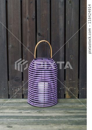 violet rattan lantern candlestick with white candle inside on wooden background . High quality photo 118424914