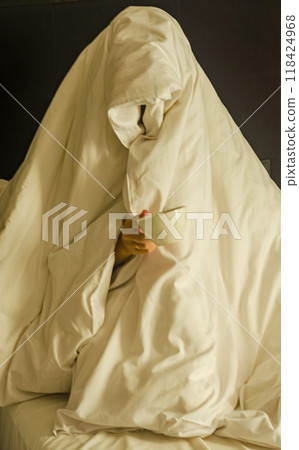 a person wrapped entirely in a blanket, resembling a ghost, holding a cup. High quality photo a person wrapped entirely in a blanket, resembling a ghost, holding a cup. High quality photo 118424968