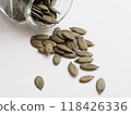 Pumpkin seeds spilled from a glass jar 118426336