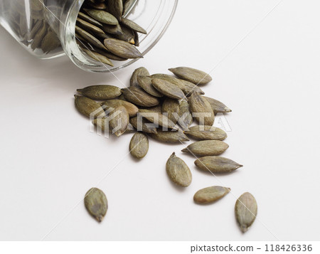 Pumpkin seeds spilled from a glass jar 118426336