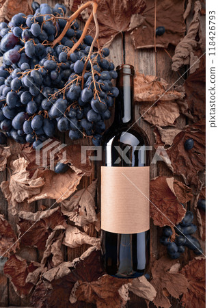 Bottle of red wine, blue grapes and dried-up vine leaves. 118426793