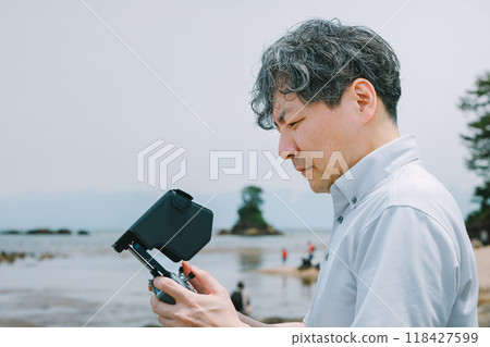 Man flying a drone on the beach Man flying a drone on the beach 118427599