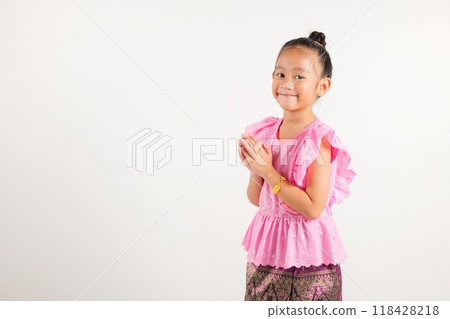 Portrait of Thailand kid girl smiling traditional Thai dress costume posing to pay respect in studio shot isolated white background, Happy kindergarten child sawasdee symbol or welcome 118428218