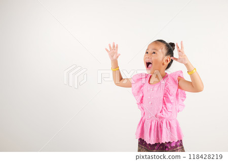 Portrait Thailand kid girl smiling traditional Thai dress costume raises fists in celebration of her success, studio isolated white background, kindergarten child saying yes with excitement winning Portrait Thailand kid girl smiling traditional Thai dress costume raises fists in celebration of her success, studio isolated white background, kindergarten child saying yes with excitement winning 118428219