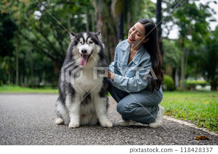 A woman is sitting and talking with her Siberian husky while taking it for a walk in the park. A woman is sitting and talking with her Siberian husky while taking it for a walk in the park. 118428337