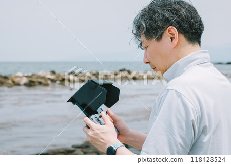 Man flying a drone on the beach Man flying a drone on the beach 118428524