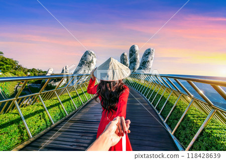 Women tourist holding man's hand and leading him to Golden bridge in Da nang, Vietnam. 118428639