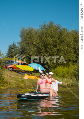 Women Enjoying Paddleboarding on a Sunny Day 118428917