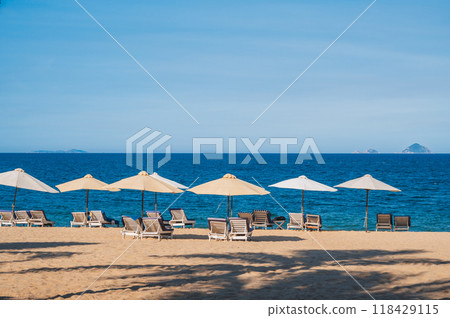 beach umbrellas with sun beds without people on a sandy beach against the background of the sea or ocean. 118429115