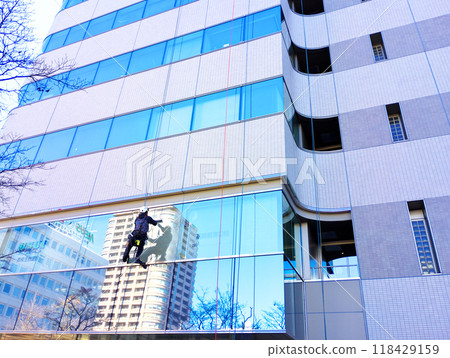 A cleaner is polishing the windows of a building A cleaner is polishing the windows of a building 118429159