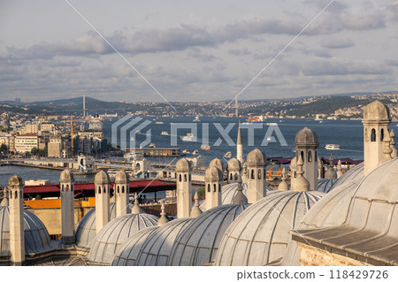 The Bosphorus Strait glistens under the sun, with boats crossing the waters and iconic rooftops of Istanbul seen in the foreground. 118429726