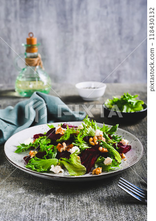 Delicious salad of beetroot, lettuce, nuts and ricotta on a plate on the table vertical view 118430132