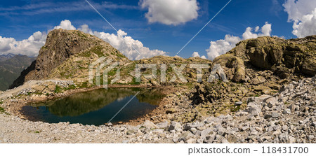 Small alpine lake reflecting rocky cliffs in a rugged mountain landscape 118431700