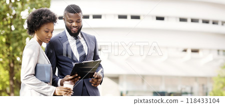 Two smiling african coworkers checking financial reports outdoors, woman having coffee, copy space Two smiling african coworkers checking financial reports outdoors, woman having coffee, copy space 118433104