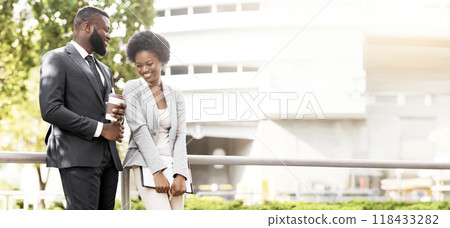 Two cheerful african american coworkers chatting outdoors during coffee break, copy space Two cheerful african american coworkers chatting outdoors during coffee break, copy space 118433282