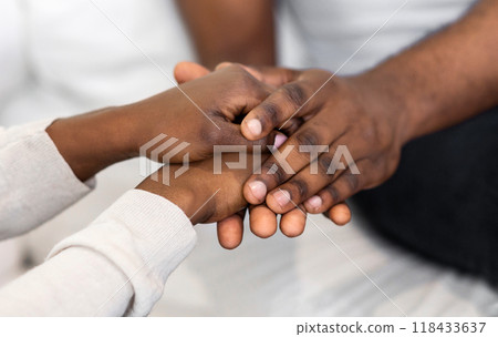Closeup image of two hands holding each other, showing a sense of connection and support. 118433637