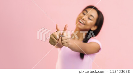Excited teen girl showing thumbs up over pink studio background, crop 118433688
