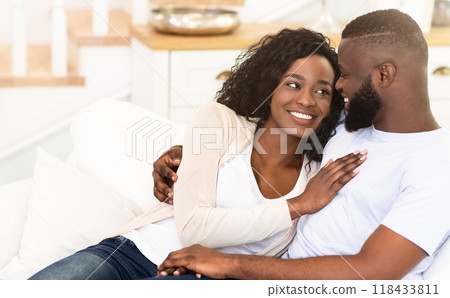 A couple is relaxing on a couch at home, looking lovingly at each other. 118433811