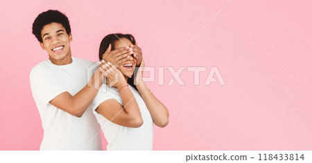 Guy covering girl's eyes, making surprise to her, pink background 118433814