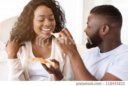 A couple enjoys a pizza together while sitting on a couch. 118433815