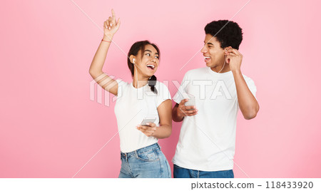 Happy students dancing and listening music by earphones over pink studio background 118433920