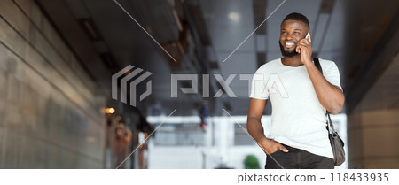 Successful african american guy talking on cellphone and smiling inside business center, panorama, copy space 118433935