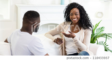 A woman sits on a couch and talks to a man, smiling and gesturing with her hands. A woman sits on a couch and talks to a man, smiling and gesturing with her hands. 118433937